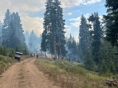 Firefighters lay hose along road used as containment line 7.12.26