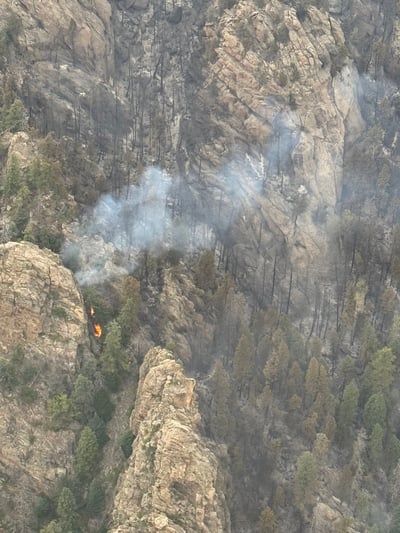 Photo shows fire creeping through the jagged rocks above Jackson Camp